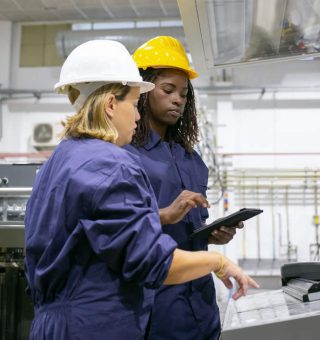 Empregada industrial feminina ensinando colega a operar a máquina